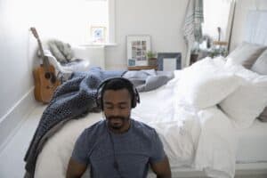 Man meditating in room wearing headphones