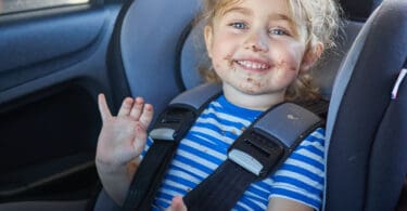 Little girl, baby in a safety car seat. Safety and Security with food all over