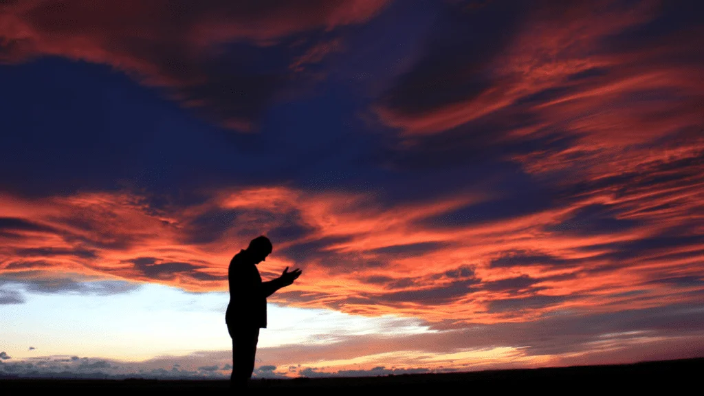 Man outside open space at dusk meditating