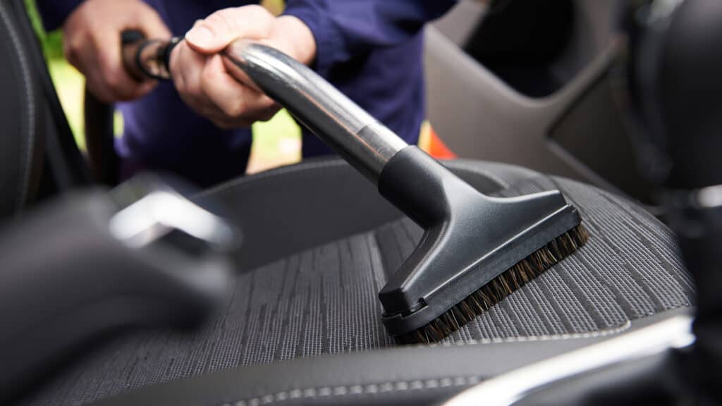 Person vacuum cleaning car
