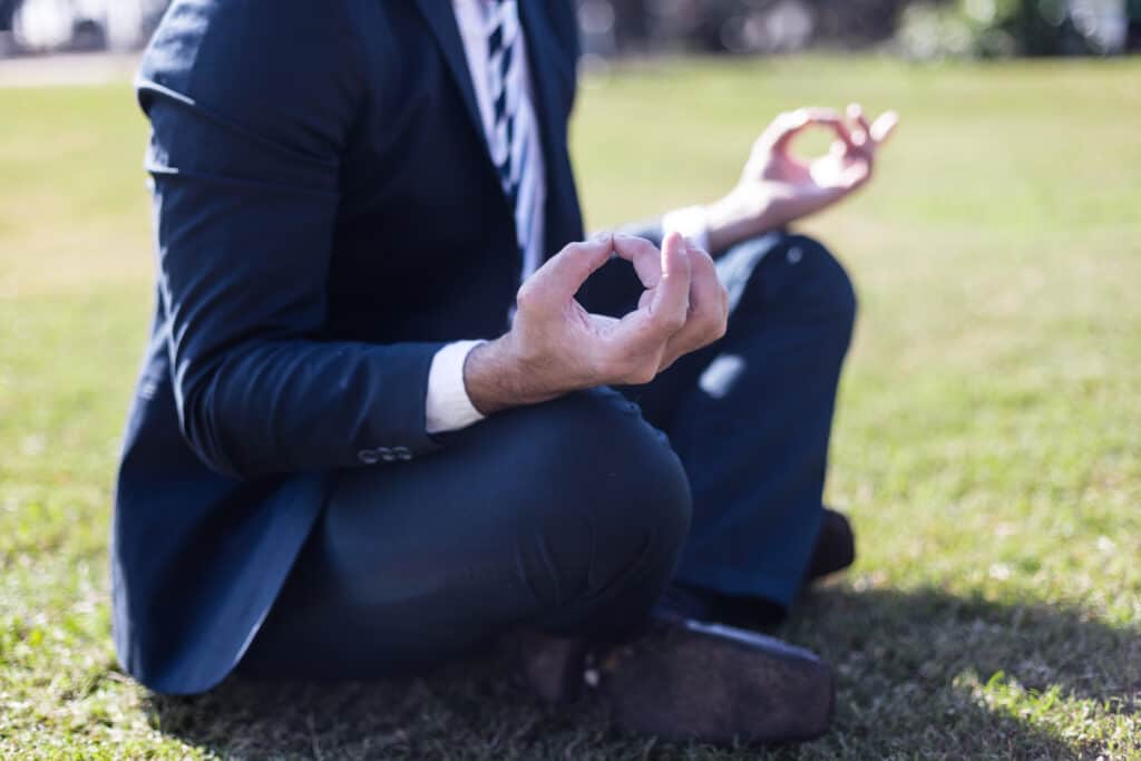 Man in suite meditating on park lawn