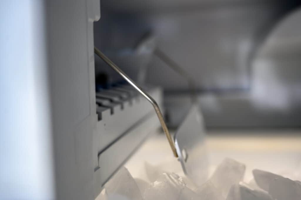 Inside a freezer automatic ice maker with pile of cubes